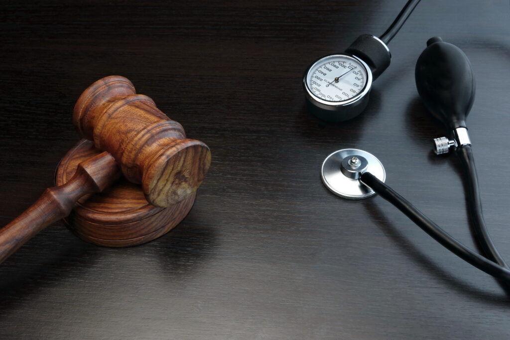 Judges Gavel And Medical Equipment On Black Wooden Background