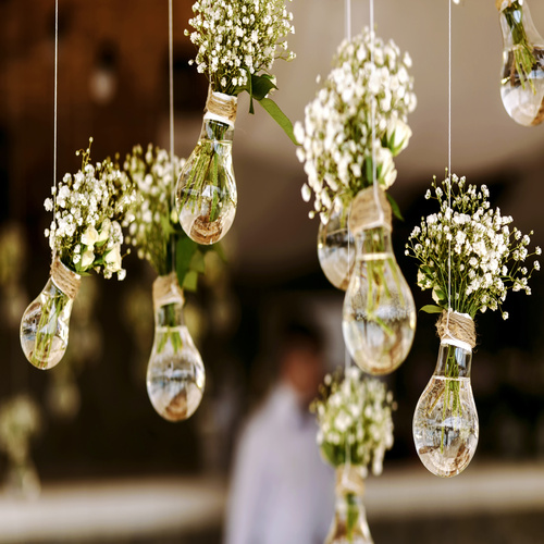 Flower bouquets used as decor at a wedding venue. The flowers are sitting in glass vases, hanging by a white string.